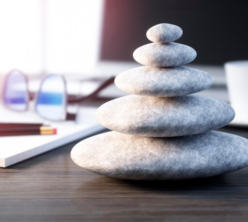 wellness/relaxation stone on desk with coffee cup, notebook, pens and glasses