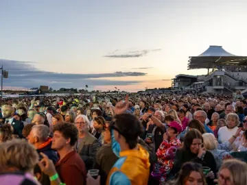 A large crowd at Bath Races enjoying live music in the sunset