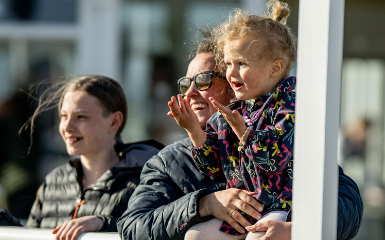 Mother and daughter smiling at the horses in the parade ring