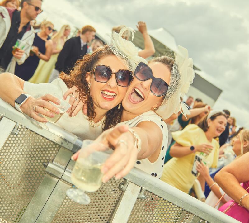 Two race goers at Bath smile and pose for the camera