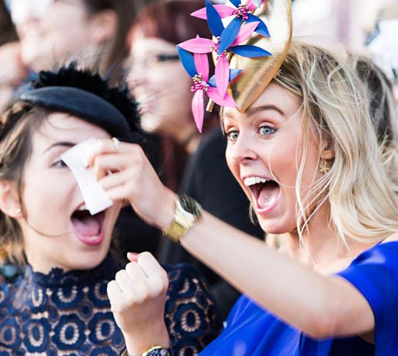 Two ladies cheering while at the races.