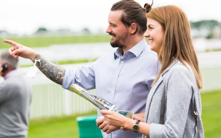 A couple at Bath Racecourse study the racecard