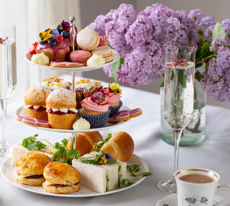 afternoon tea on a 3 tiered cake stand, with cups of tea and glasses of prosecco
