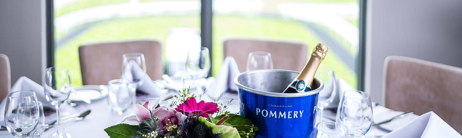 Close up on a table in restaurant with glasses, plates, napkins and a bottle of champagne.