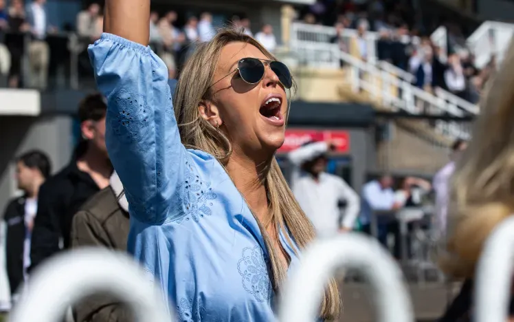 A racegoer at Bath Racecourse cheers excitedly for a race