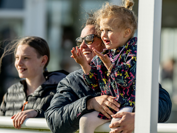 Mother and daughter smiling at the horses in the parade ring