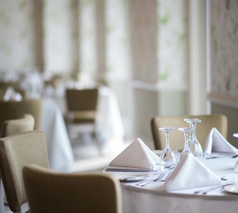 Close up on a table inside Mornington Suite, with glasses, napkins and cutlery set up on it.