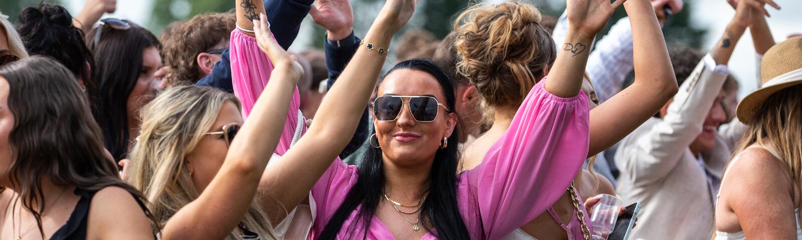 Group of women with their hands in the air dancing along to a DJ set